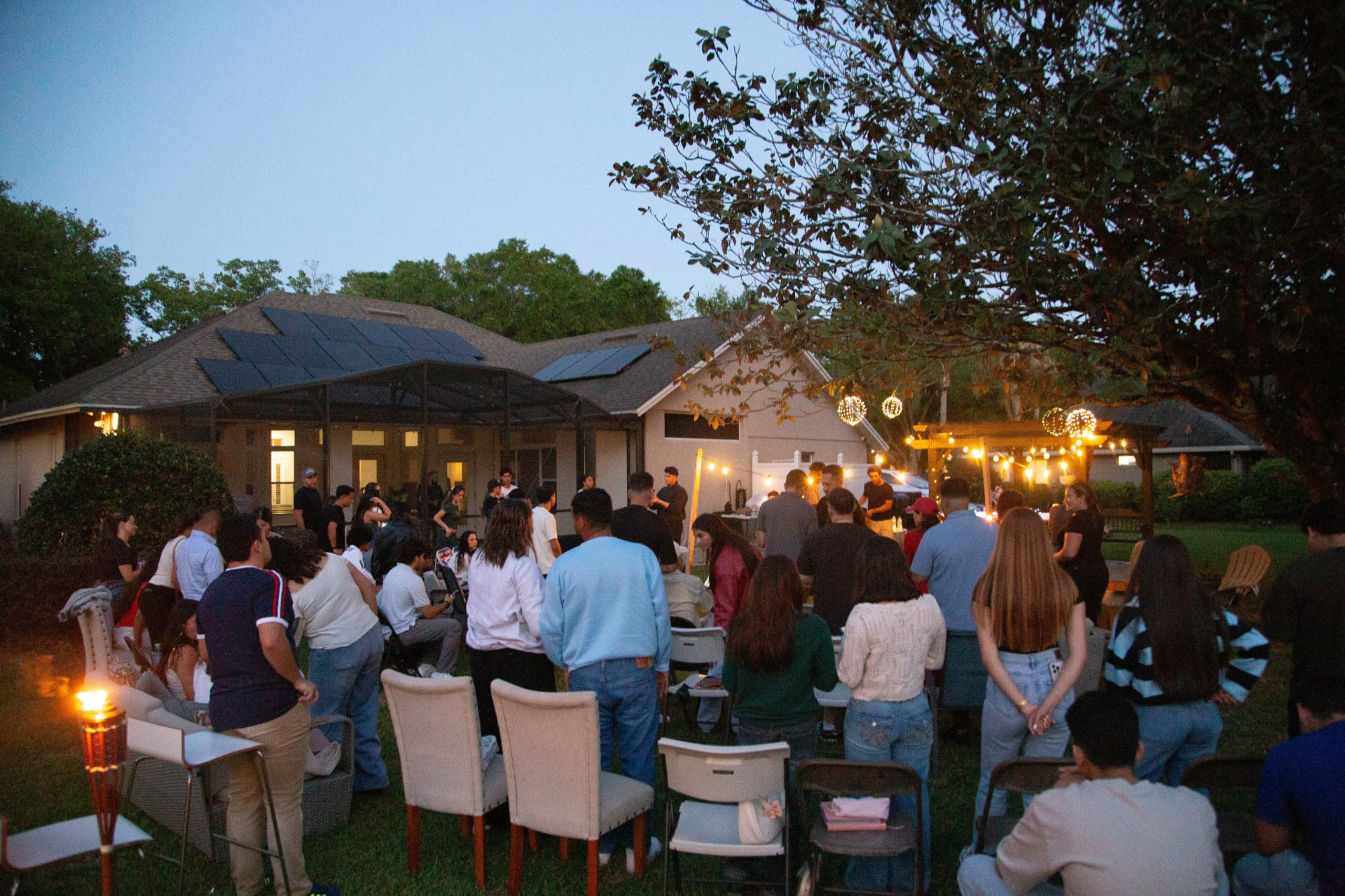 Backyard worship night at dusk with string lights